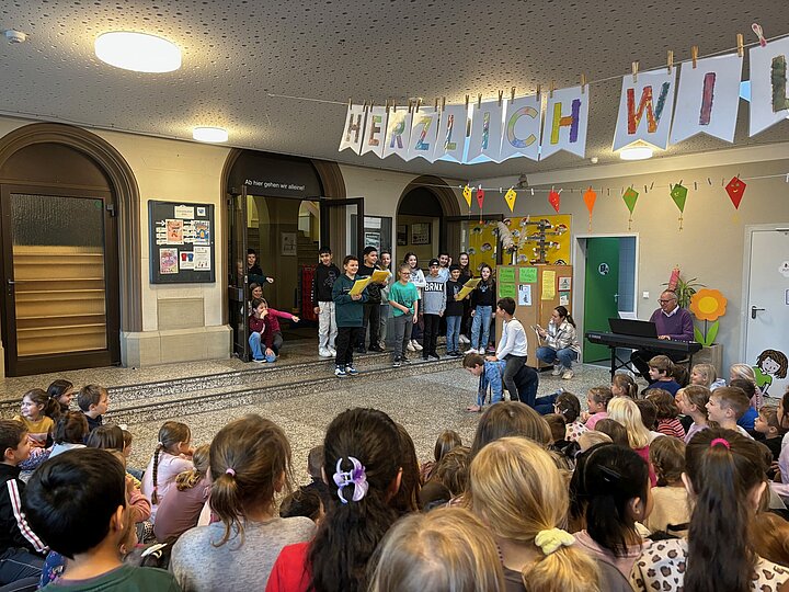 Kinder lauschen dem Liedbeitrag der Klasse 4c